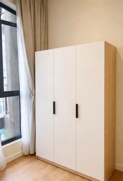 Room features: white wardrobe with three doors, wooden base, black handles, light-colored walls, floor-to-ceiling window, sheer curtains, laminate flooring; style: modern.