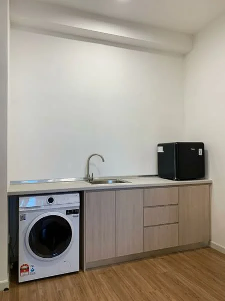 Kitchen features: single-bowl stainless-steel sink, chrome pull-down faucet, light wood cabinetry, built-in washing machine, black refrigerator, countertop with silver trim, wood laminate flooring, white painted walls; style: modern.