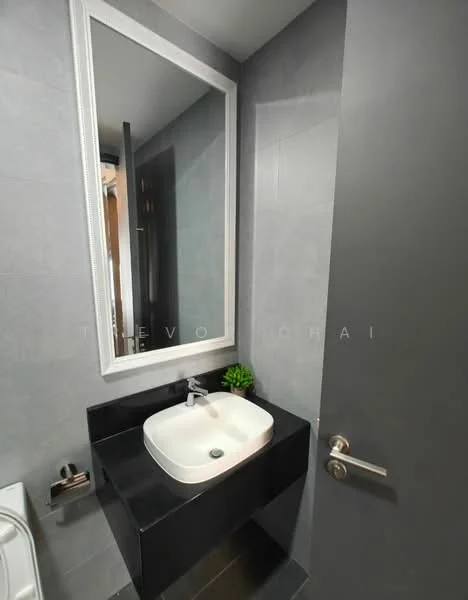 Bathroom features: grey tiled walls, black countertop, white basin sink, chrome faucet, framed mirror, wall-mounted towel holder, modern light fixture, plant decoration; style: modern.