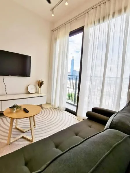 Living features: black fabric sofa, round wooden coffee table, wall-mounted TV, white TV console, floor-to-ceiling windows, sheer curtains, area rug with circular pattern, decorative plant in ceramic pot; style: modern; view: city.