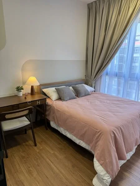 Bedroom features: queen-size bed with pink bedding, two grey decorative pillows, wooden bedside table, table lamp with warm light, curtains in light beige, floor-to-ceiling windows, wooden flooring, small potted plant on bedside table, study desk with chair; style: modern.