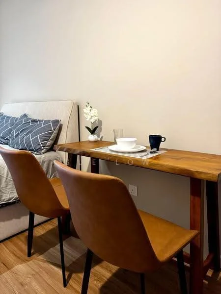 Dining features: wooden dining table, two brown leather dining chairs, white ceramic plate, clear glass drinking glass, blue ceramic mug, decorative white orchid plant, grey wall, wooden flooring; style: modern. Room features: bed with upholstered headboard, grey bedding, grey and white striped throw pillows.