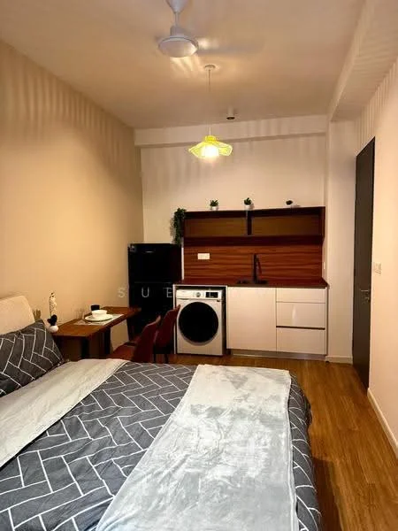 Room features: queen-size bed with grey geometric patterned bedding, wooden bedside table, table lamp, black fridge, white washing machine, white cabinetry, wooden countertop, black sink, chrome faucet, pendant light, wooden flooring, ceiling fan; style: modern.