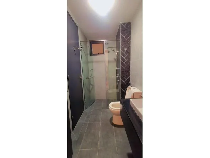 Bathroom features: glass shower enclosure, rain shower head, handheld shower, one-piece toilet, vanity with sink, mirror above vanity, grey tile flooring, dark accent wall, light fixture on ceiling, wall-mounted towel rack; style: modern.