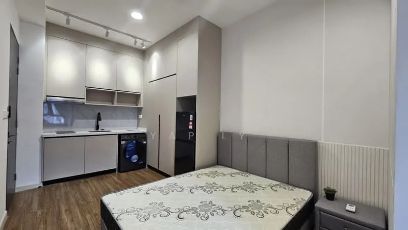Room features: grey upholstered bed frame, mattress on bed, white painted walls, laminate flooring, kitchen cabinetry with flat-panel design, black countertop, single-bowl stainless-steel sink, chrome pull-down faucet, built-in oven, stainless-steel fridge, front-load washing machine, recessed downlights, wall-mounted light fixture; style: modern.