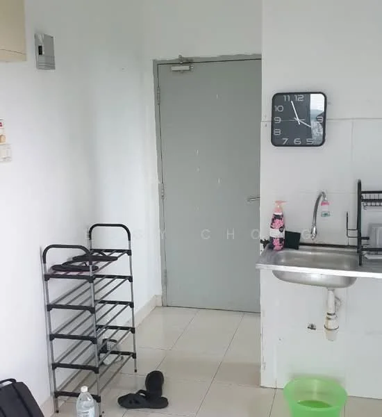 Room features: white painted walls, tile flooring, grey door, wall clock, single-bowl stainless-steel sink, kitchen faucet, metal shelving unit, water bottle, black slippers, green plastic basin.