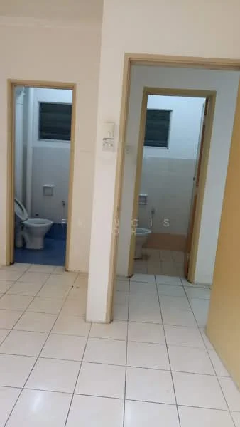 Room features: white tiled flooring, plain white walls, two doorways leading to bathrooms, one bathroom with blue flooring, one bathroom with beige tiled walls, visible toilet in one bathroom, window in bathroom, light switch on wall.