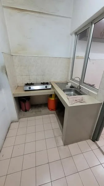 Kitchen features: single-bowl stainless-steel sink, chrome faucet, 2-burner gas hob, light-colored tiled backsplash, cream-colored countertop, pink trash bin, yellow gas cylinder, white tiled flooring, white painted walls, window with metal frame.