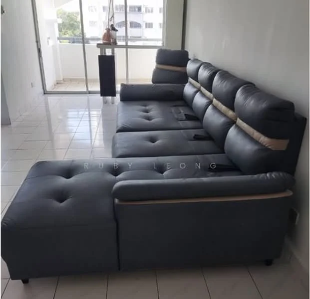 Living features: L-shape sectional sofa in grey, tufted upholstery, armrest with built-in cup holders, white tiled flooring, large glass sliding door, natural light from outside, neutral wall color, decorative plant on side table; style: modern.