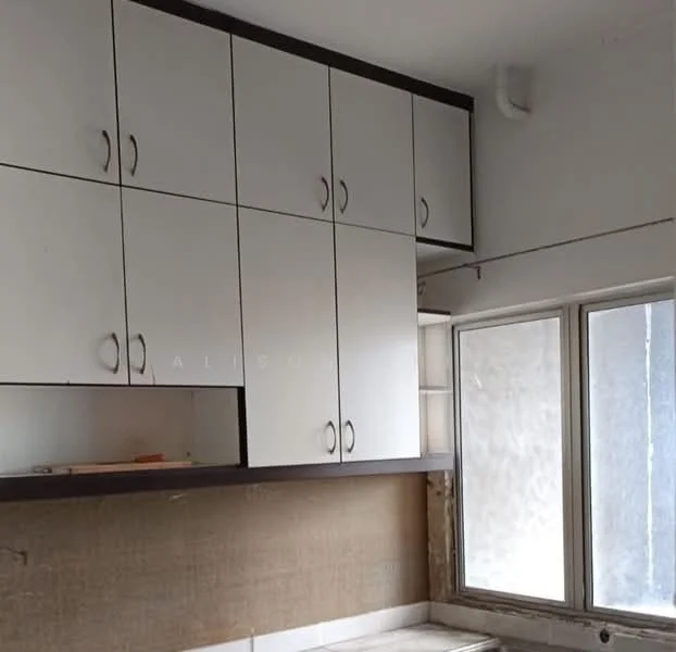 Kitchen features: upper cabinetry with white doors, dark wood trim on cabinets, window with white frame, countertop with beige surface, wall with beige wallpaper, light fixture on ceiling, exposed wall area, splashback area.