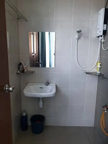 Bathroom features: wall-mounted shower head, chrome faucet, white ceramic sink, mirror above sink, tiled walls, grey floor tiles, shower water heater, shelf next to shower, waste bin, cleaning supplies, blue bucket; style: modern.