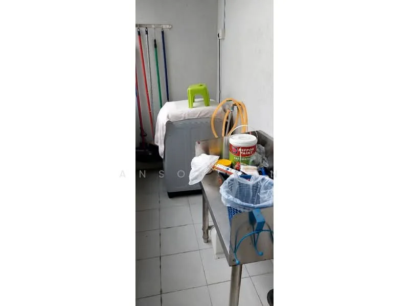 Laundry features: white tiled flooring, grey walls, stainless-steel sink, metal work table, plastic chair, cleaning supplies, laundry basket, hanging rods for clothes.