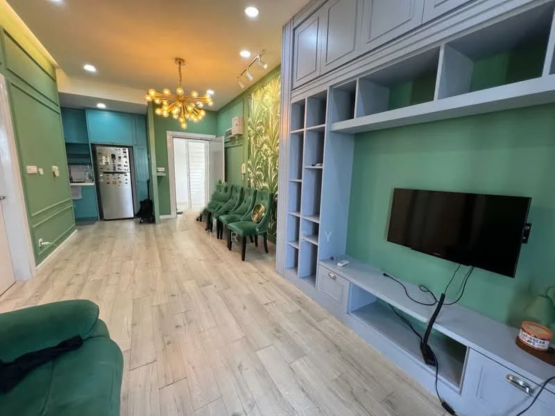 Living features: green accent wall, light grey walls, wood-look tile flooring, 5-blade ceiling fan with light, wall-mounted TV, built-in shelving unit, sofa in green fabric, decorative wall art, recessed lighting, open layout to kitchen, large windows for natural light; style: modern. Kitchen features: stainless-steel fridge, built-in cabinets, countertop with appliances, kitchen island, open layout to living area; style: modern.