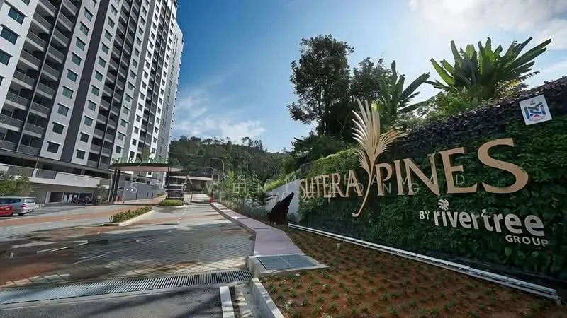 Exterior type: high-rise condominium; features: modern facade with glass curtain wall, landscaped entrance with greenery, feature wall with branding, paved driveway, surrounded by tropical landscaping, multi-storey building, guard house at entrance, parking area visible; style: modern.