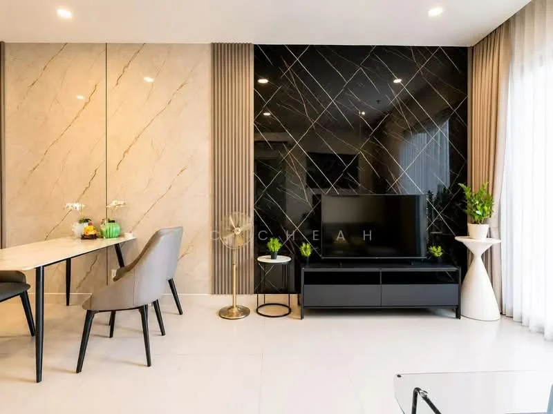 Living features: black marble accent wall with gold veining, light beige marble wall, white tiled flooring, flat-screen TV on black console, black console with storage, gold floor lamp, decorative white planter, green plants, dining table with grey upholstered chairs, sheer curtains, recessed ceiling lights; style: modern.