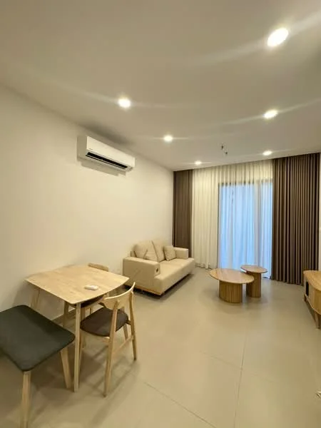 Living features: 3-seater fabric sofa in beige, 2 round coffee tables in wood, dining table with 2 chairs, 1 grey upholstered dining chair, floor-to-ceiling sliding glass door, sheer curtains, recessed LED downlights, wall-mounted split AC, light grey tiled flooring, white painted walls, accent wall with vertical stripes in brown, decorative wall paneling; style: modern.