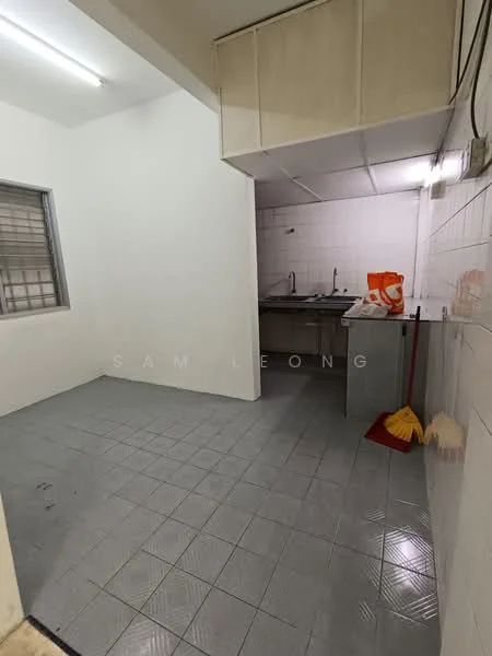 Kitchen features: white painted walls, grey tiled flooring, single-bowl stainless-steel sink, chrome pull-down faucet, wall-mounted cabinets, countertop, window with security bars, lighting fixtures, cleaning supplies visible.