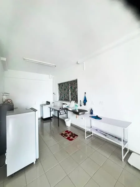 Laundry features: white walls, grey tiled flooring, single-basin stainless-steel sink, white washing machine, metal folding table, window with patterned curtain, small area rug, white countertop, plastic bucket, cleaning supplies on countertop.