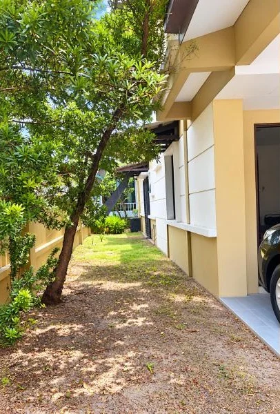 Exterior type: detached bungalow; features: double-storey, cream painted facade, white painted facade accents, projecting eaves, flat roof, side yard with grass, mature trees, tropical landscaping, stone-paved or compacted earth side walkway, car porch with awning, covered parking, driveway with tiled floor, fronts a quiet residential street; style: contemporary.