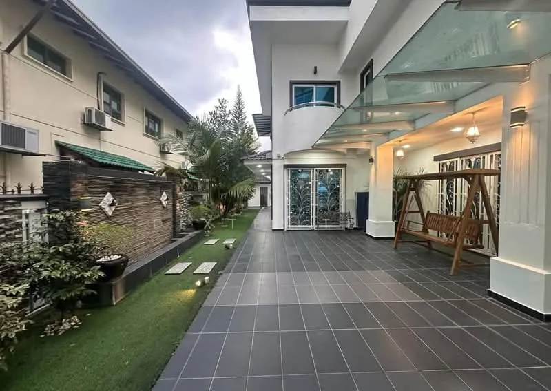 Exterior type: detached bungalow; features: covered porch area, swinging bench, tiled flooring, landscaped garden with grass, paved walkway, exterior wall with decorative elements, outdoor lighting fixtures, palm trees, fenced perimeter, air conditioning units on the wall; style: modern.