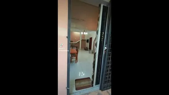 Room features: white painted walls, glossy tile flooring, dining table with chairs, staircase visible in background, hanging pendant lights, open layout, doorway leading to another room; style: modern.