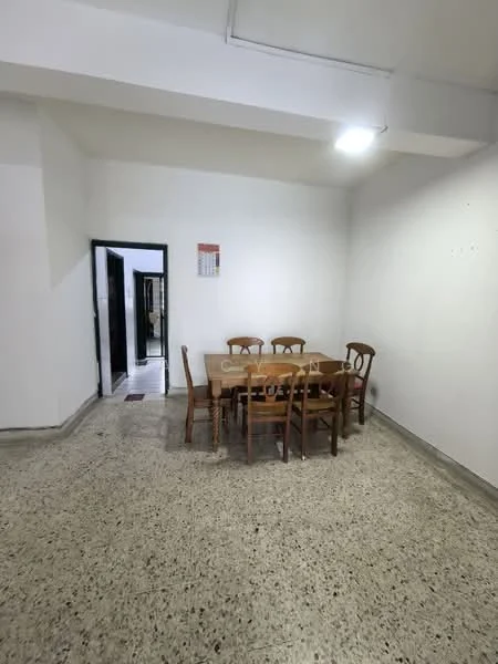 Dining features: wooden dining table with six chairs, white painted walls, polished concrete flooring, ceiling light fixture, calendar on wall, doorway leading to another room.