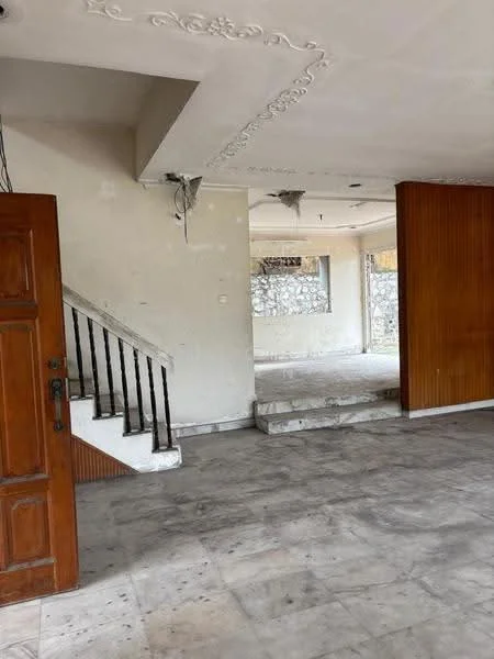 Room features: white painted walls, exposed ceiling with decorative moulding, marble flooring, staircase with black metal railing, open space layout, large window with stone wall backdrop, wooden door, wood paneling on one wall; style: traditional.