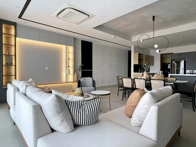 Living features: light grey fabric sectional sofa, black and white patterned throw pillow, beige throw pillow, round coffee table, built-in shelving with backlighting, wall-mounted TV, recessed ceiling lights, exposed concrete ceiling, open-plan layout, large windows, neutral wall color, tile flooring; style: modern. Dining features: dining table with black surface, rattan dining chairs, pendant lighting above dining area, open kitchen layout, kitchen island, stainless-steel appliances; style: modern.