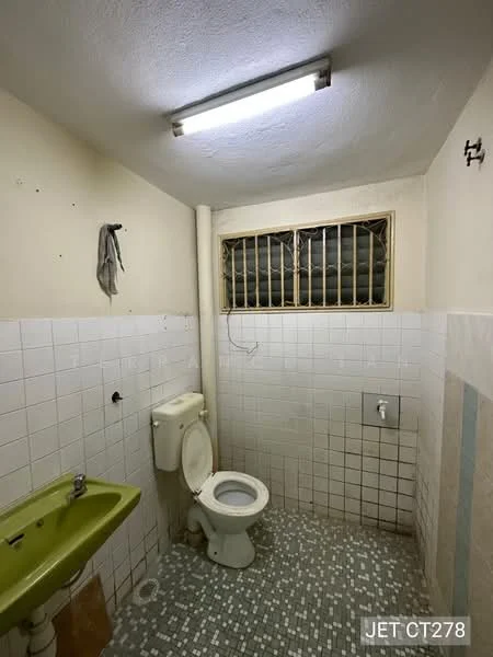 Bathroom features: white tiled walls, green ceramic sink, white toilet, shower area with tiled wall, grey mosaic tile flooring, overhead fluorescent light, window with metal grille.