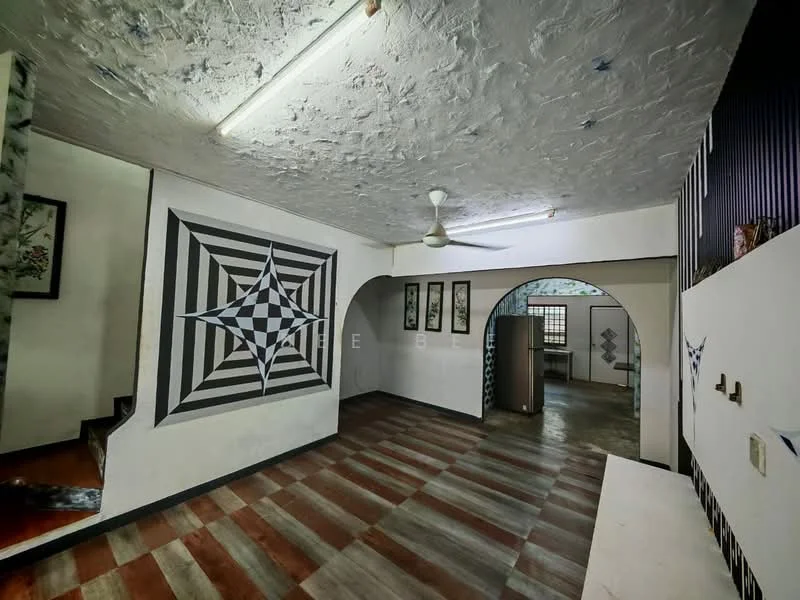 Room features: textured ceiling with fluorescent lighting, geometric wall design with black and white patterns, wooden flooring with alternating color tiles, arched doorway leading to another room, wall-mounted artwork, ceiling fan, open layout, staircase visible in background; style: modern.