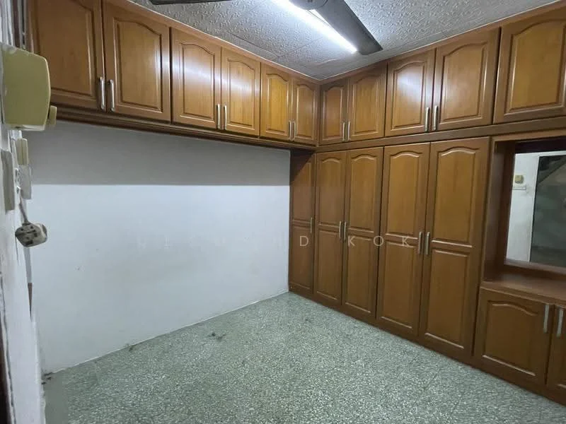 Room features: built-in wooden cabinets, green speckled flooring, ceiling fan, plain white walls, window with wooden frame, no visible lighting fixtures, corner shelving unit.