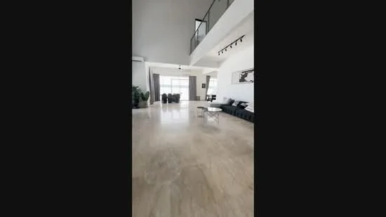Living features: marble flooring, high ceiling, large floor-to-ceiling windows, grey sectional sofa, coffee table, track lighting, decorative wall art, potted plants, curtains, open layout; style: modern; view: city.
