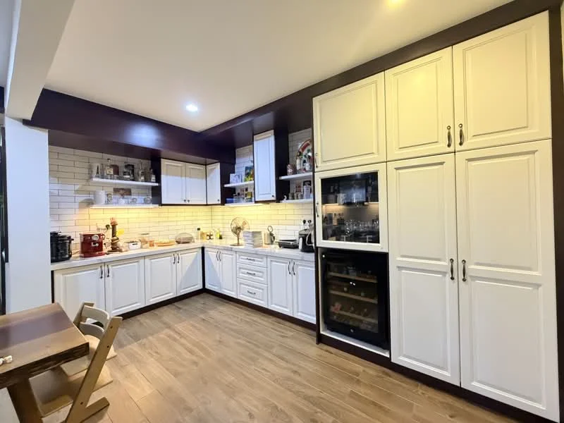 Kitchen features: white shaker cabinets, dark wood cabinetry, stainless-steel appliances, built-in oven, microwave, stainless-steel fridge, wine cooler, white subway tile backsplash, laminate countertop, wooden flooring, recessed downlights, open shelving, kitchen island, dining table, two wooden chairs; style: modern.
