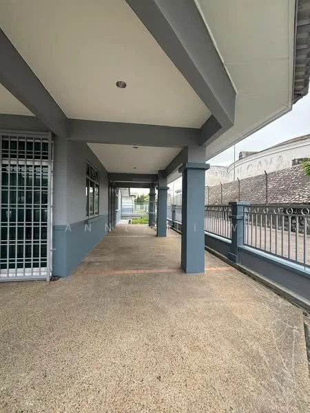 Exterior features: covered walkway, grey painted walls, concrete flooring, metal railing, large windows, overhanging roof, exposed beams, surrounding greenery; style: modern.