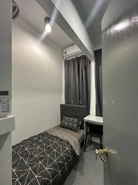 Bedroom features: single bed with grey bedding, black and white geometric patterned bedspread, grey carpet flooring, white painted walls, black curtains, wall-mounted air conditioning unit, ceiling light fixture, study desk with chair; style: modern.