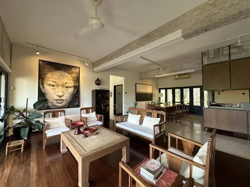 Living features: wooden flooring, exposed concrete ceiling, 5-blade ceiling fan with light, large artwork on wall, two 3-seater wooden sofas with white cushions, wooden coffee table, decorative bowls on table, potted plant, large windows with black frames, open layout to dining area; style: modern; view: garden. Dining features: wooden dining table, wooden dining chairs, open layout to living area, large windows with black frames; style: modern; view: garden.