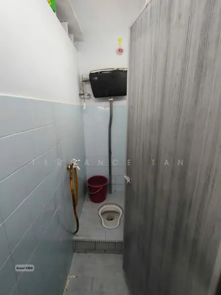 Bathroom features: blue tiled walls, grey tiled flooring, toilet, shower area, shower head, wall-mounted mirror, plumbing fixtures, bucket, hose, partition wall.