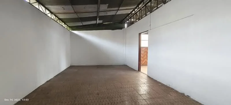 Room features: white painted walls, tile flooring, exposed ceiling, natural light from window, doorway leading to another room.