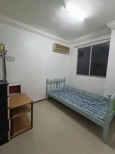 Bedroom features: single bed with light blue frame, mattress with blue patterned bedding, white painted walls, cream tiled flooring, window with white frame, wall-mounted air conditioning unit, open shelving unit, black storage cabinet.