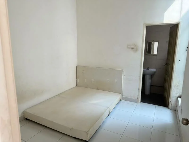 Bedroom features: white painted walls, tile flooring, single bed mattress on platform, window with natural light, door leading to bathroom, small mirror above sink in bathroom, bathroom door, minimal decor.