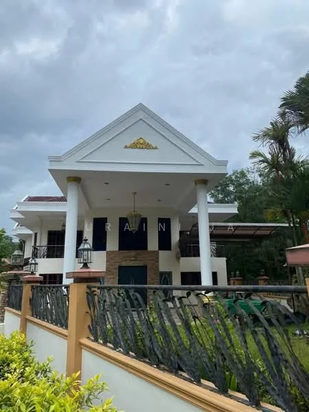 Exterior type: detached bungalow; features: white painted facade, gabled roof, stone cladding at entrance, columns at entrance, decorative gold detailing, landscaped garden, manicured lawn, paved walkway, outdoor lighting fixtures, surrounded by greenery; style: modern.