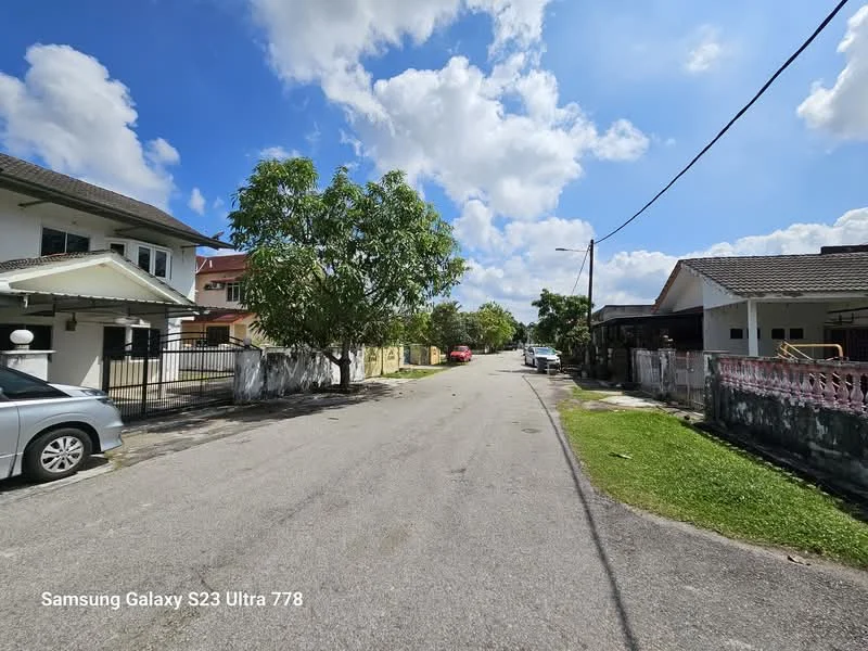 Exterior features: residential street, paved road, green grass, mature trees, single-storey houses, two-storey houses, clear blue sky, scattered clouds.
