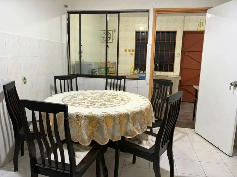 Dining features: round dining table with lace tablecloth, 6 black wooden dining chairs, white tiled flooring, white painted walls, window with black metal grille, view into kitchen area, door leading to kitchen, decorative wall clock. Kitchen features: white tiled walls, brown wooden cabinets, kitchen countertop visible, sink visible through window, kitchen appliances visible.