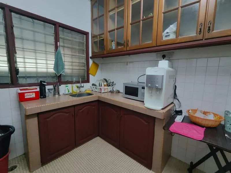 Kitchen features: brown wooden cabinetry, white tiled walls, beige tiled flooring, double-bowl stainless-steel sink, chrome faucet, built-in microwave, water dispenser, countertop with rounded edges, open shelving, kitchen utensils, dish rack, trash bin.