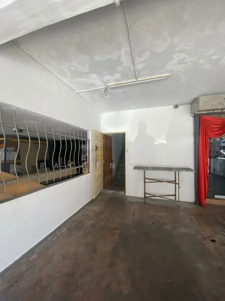 Room features: white painted walls, exposed concrete ceiling, concrete flooring, metal railing, stainless-steel table, wooden door, staircase leading to upper level, large window opening, red curtain draped, light fixture on ceiling; style: minimalist.