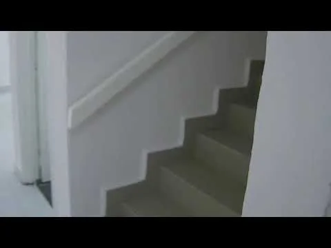 Room features: white painted walls, light grey flooring, staircase with white railing, steps with a straight edge; style: modern.