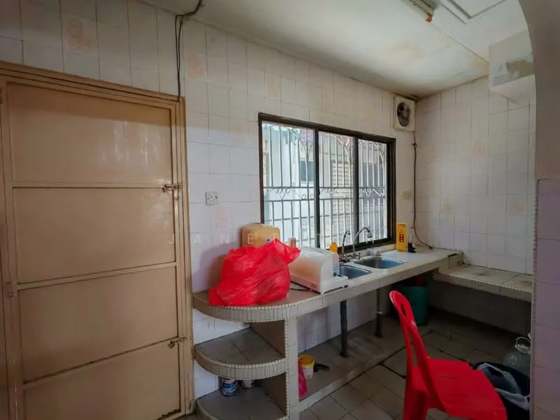 Kitchen features: single-bowl stainless-steel sink, chrome pull-down faucet, white tiled walls, grey tiled flooring, wooden cabinetry, countertop with storage underneath, window with metal grille, exposed electrical wiring, plastic chair in red, various kitchen items on countertop.