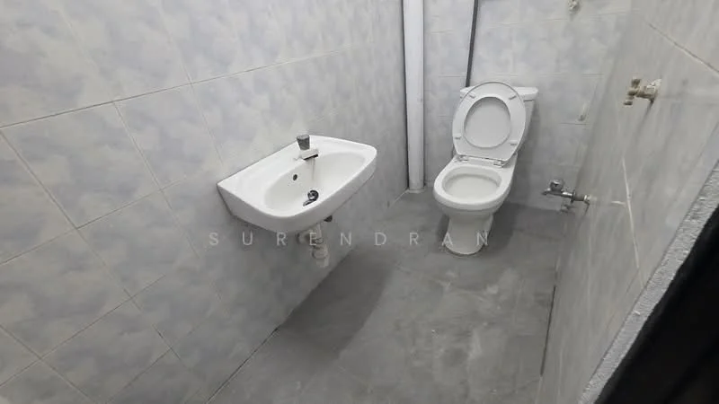 Bathroom features: white ceramic toilet, white wall-mounted sink, chrome faucet, grey tile flooring, light blue patterned wall tiles, exposed plumbing, single towel rail, no visible storage.