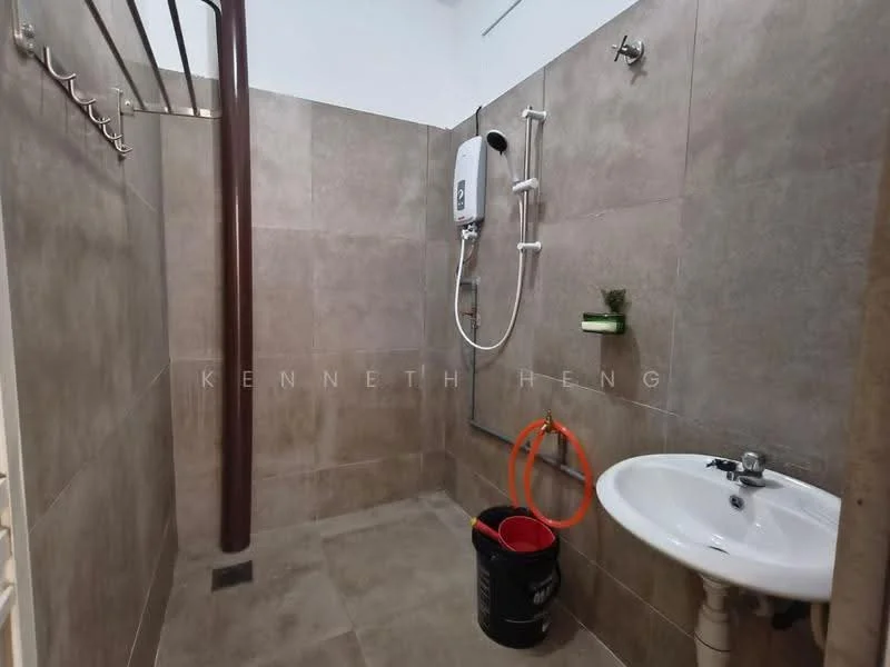 Bathroom features: grey tiled walls, grey tiled flooring, shower area with wall-mounted shower head, handheld shower, water heater, white pedestal sink, chrome faucet, towel rack, bucket, orange hose, small plant decoration; style: modern.