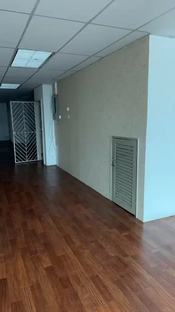 Room features: wooden flooring, cream wallpaper with pattern, air vent, wall-mounted electrical outlets, white ceiling, fluorescent ceiling lights, partition wall, open space layout.